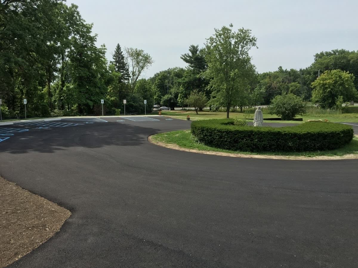 Freshly sealcoated commercial parking lot surrounded by trees
