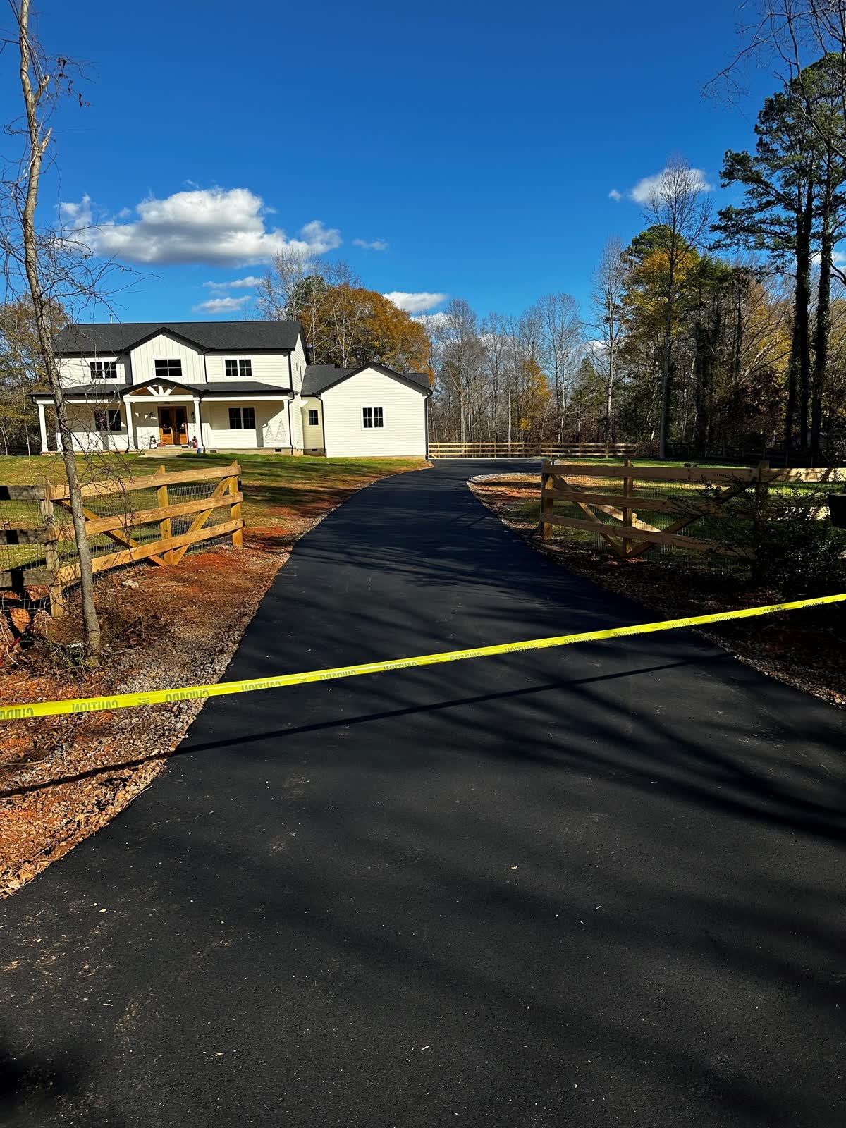 Fresh asphalt driveway at a two-story brick home on a sunny Washington afternoon
